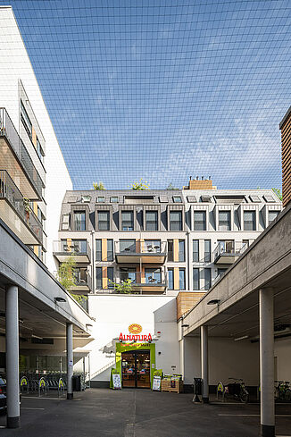 An entrance with parking spaces for the Alnatura market is located in the inner courtyard of the residential neighbourhood.