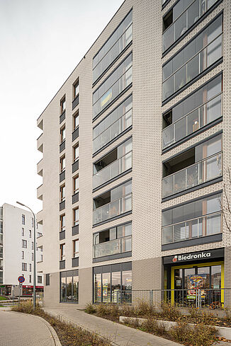 Side view of a building in Warsaw with a supermarket on the ground floor and flats above.
