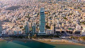 Aerial view of the luxury residential tower ONE with the city of Limassol in the background.