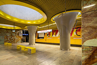 Modern waiting area with yellow walls and benches in a metro station in Warsaw.