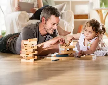 A man plays with a child on a wooden floor.