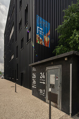 Black façade with advertisement for a restaurant on a building of the office and commercial building Pôle PIXEL in France.