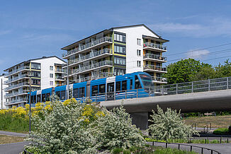 Railway bridge with train and two buildings in background