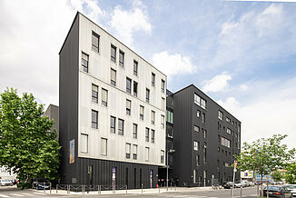 Exterior view from the street of the black and white façade with windows of the Pôle PIXEL office and commercial building in France.