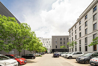 Building complex with cars parked in the courtyard in the Pôle PIXEL industrial estate in France.