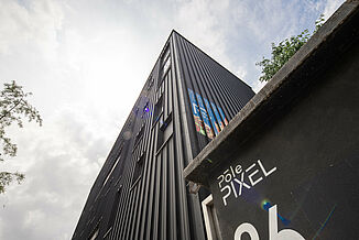 Black façade with advertising and windows on a building of the office and commercial building Pôle PIXEL in France.