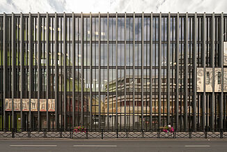 A dark façade with many windows of the Léo Délibes music school directly on a street in Paris.