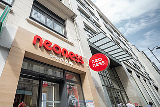 Façade of a residential and commercial building in Paris with a neoness fitness studio on the ground floor and flats above.
