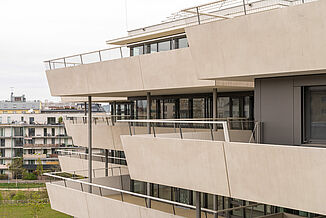 Side view of a building section with surrounding terraces of the Aaron Mencer Campus in Vienna.