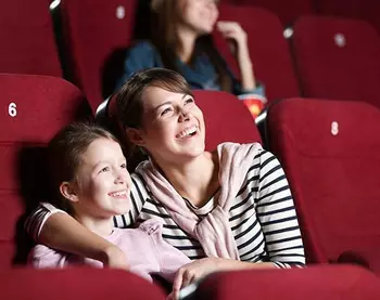 A woman is sitting in the cinema with a child.
