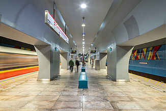Waiting area with ceramic floor and blue benches in a metro station in Warsaw.