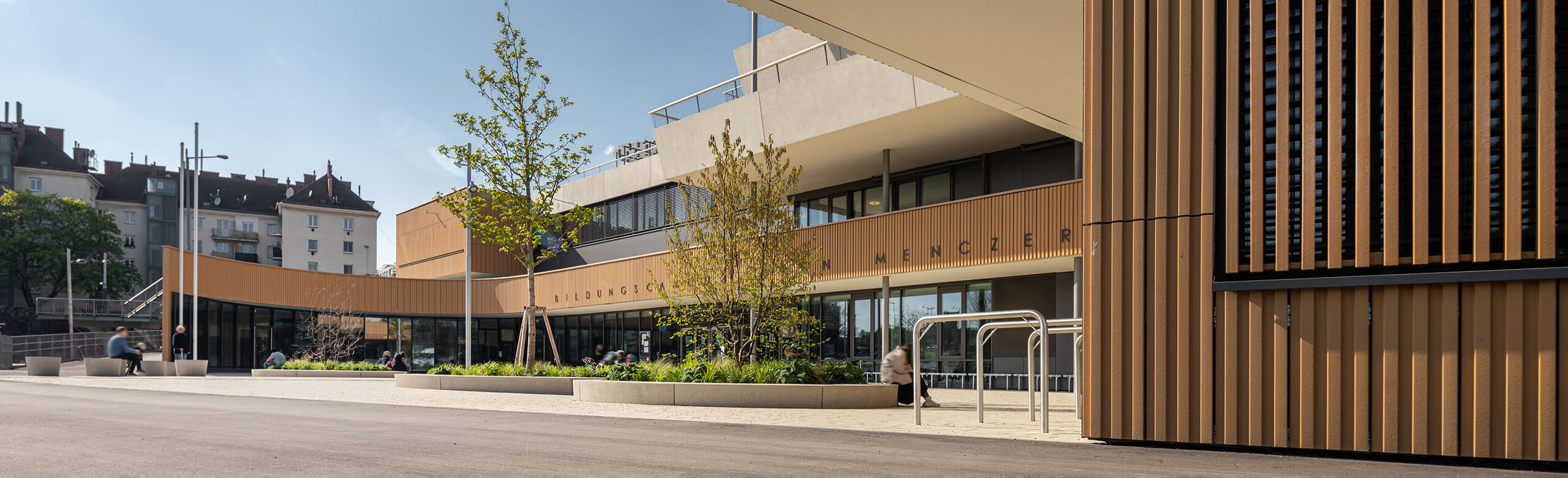 Entrance area with wooden façade of the Aaron Mencer Campus in Vienna.